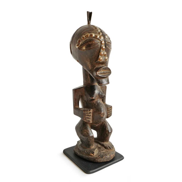 Original rare antique wood carved Songye figure with nail head detail from Democratic Republic of Congo. Displayed on iron...