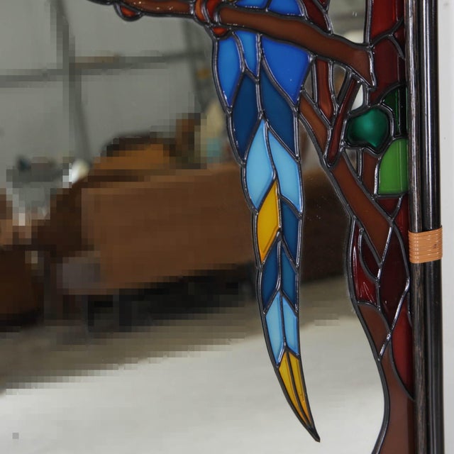Stunning stained-glass mirror depicting a parrot. Very decorative with its blackened rattan frame and vibrant colors, it...