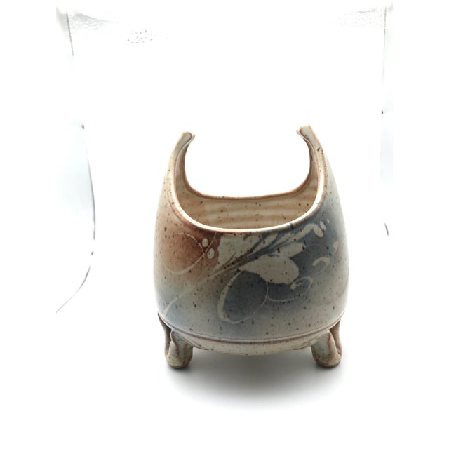 Signed on the bottom but we can’t quite make it out. Look’s adorable with a funky plant!