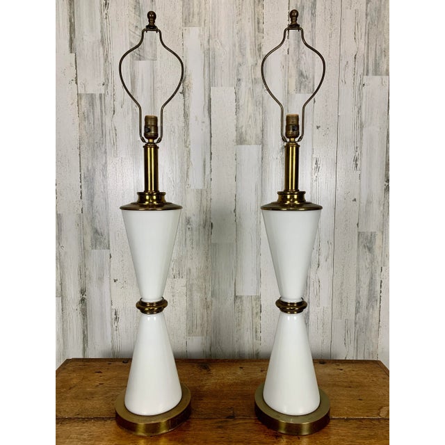 A pair of 1960s white milk glass inverted cones separated with brass accents for a hourglass silhouette. The top of the...