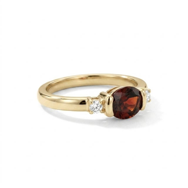 Sophisticated, contemporary, and beautifully minimalist. This exquisite three-stone ring features a stunning 6x4mm oval-...