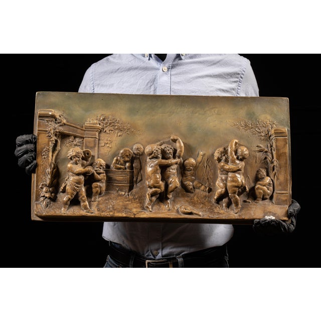 Decorative cast-plaster relief plaque rendered in the Neoclassical style with a warm, bronze-toned finish. The lively...