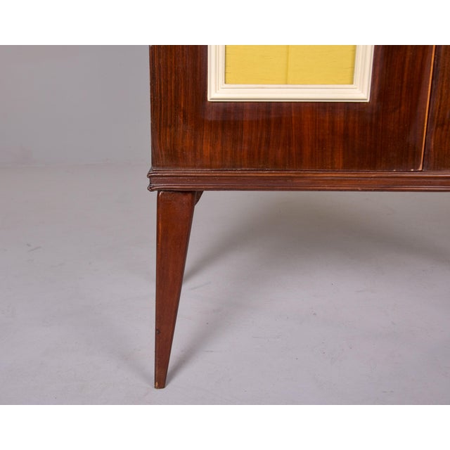 Found in Italy, this walnut bar cabinet dates from the 1950s. This cabinet has two locking hinged doors with yellow glass...