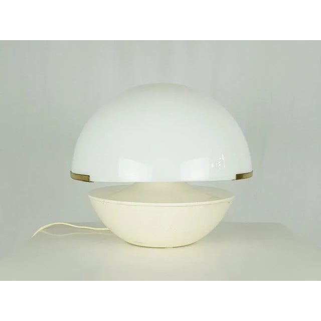 Table lamp produced in the late 60s in Italy. Ivory white metal body with brass support structure and hemispherical white...