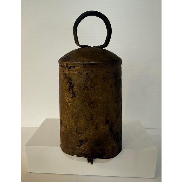 A beautifully aged antique hand-forged iron livestock bell featuring a classic tapered form with riveted seam construction...