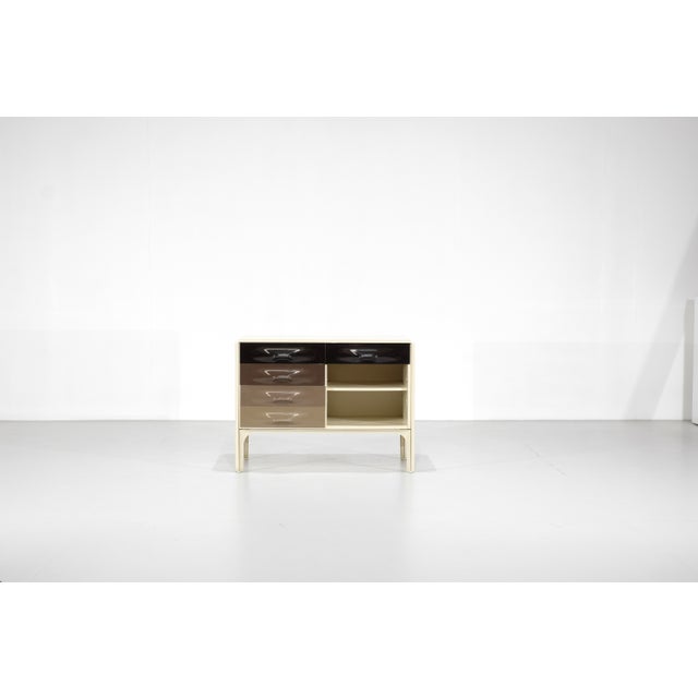 "DF 2000" desk with a pull-out shelf and two molded plastic drawers in a gradient of colors, transitioning from dark brown...