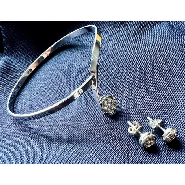 A high-quality white gold bundle of 585 white gold open bangle with 7 brilliants and 585 white gold stud earrings with 6...