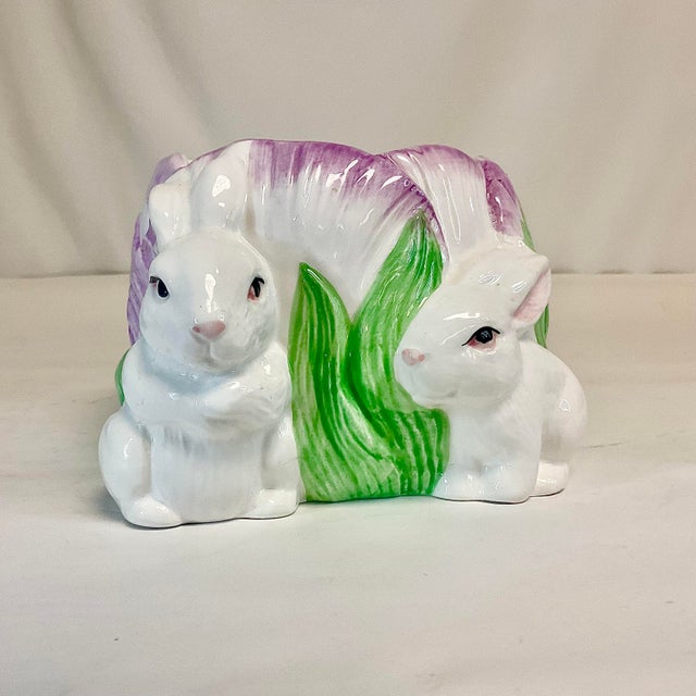 Vintage Home is pleased to offer this lovely ceramic planter. It features two white bunnies sitting next to a large violet...