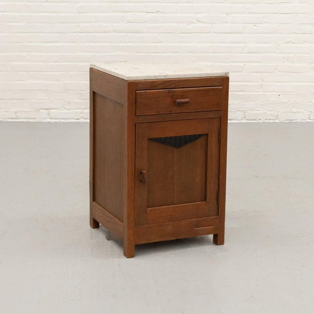 Dutch Art Deco bedside cabinet dating from circa 1925–1930, crafted in oak and oak veneer with a white-veined marble top....