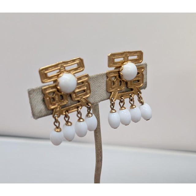 1960s goldtone Asian character with cabochon white rhinestone in the center with four ovoid white bead drops clip back...