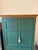 Handsome painted wood armoire featuring a muted sage green finish with a contrasting natural wood crown. Paneled double...