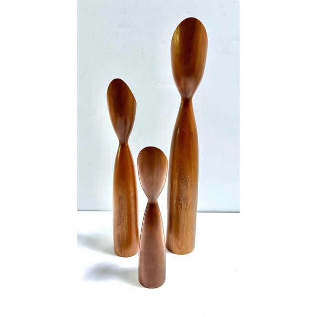 A sculptural set of three signed Danish teak candle holders with elongated turned forms and asymmetrical tulip-shaped...