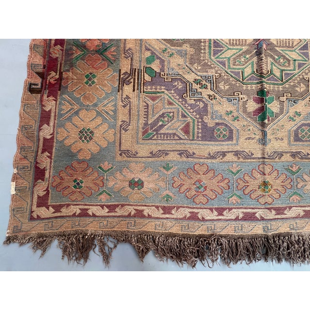 A large antique Caucasian rug with the soft, sun-faded palette collectors chase — a vertical pole-column of hooked, star-...