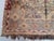 A large antique Caucasian rug with the soft, sun-faded palette collectors chase — a vertical pole-column of hooked, star-...