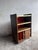 A distinctive vintage stereo cabinet dating from the 1970s. The warm wood-grain finish is contrasted by a bright red...