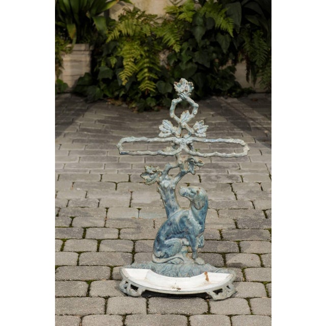 A French cast iron painted umbrella stand with dog motif from the early 20th century with enameled tray. This early 20th-...