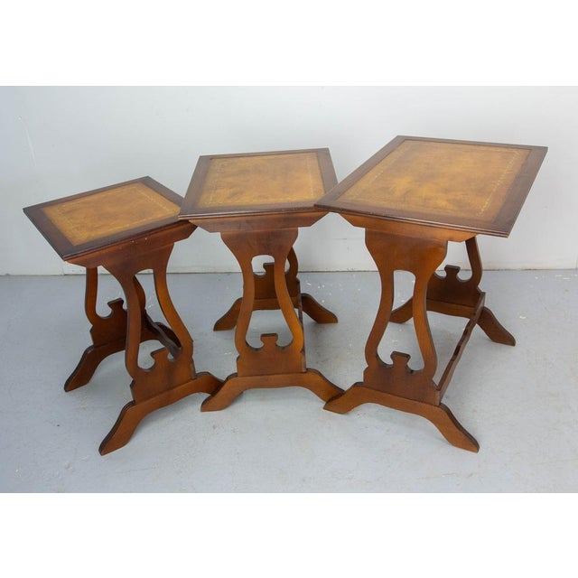 Three nesting vintage tables, French, circa 1960 The poplar tops are recovered of leather. Each leather top is framed by a...