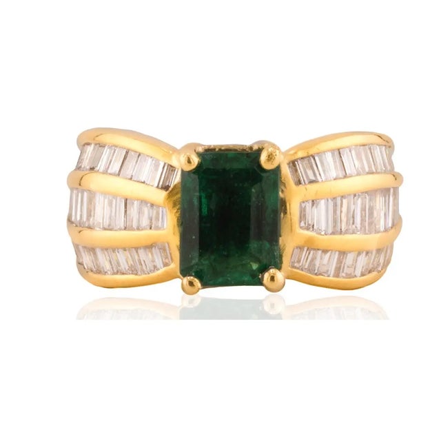 18k Ring with one emerald cut emerald weighing approximately1.50 carats and 66 baguette cut diamonds weighing...