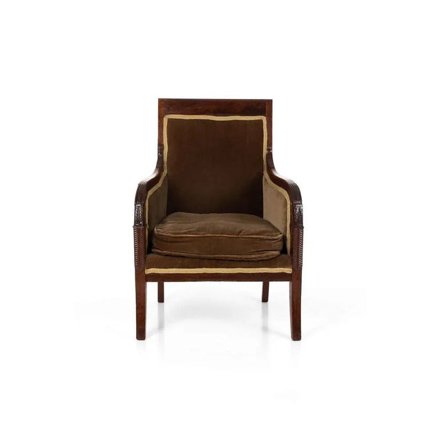A superb Regency library armchair in rosewood, raised on saber legs with foliate carving to the curve and base of the...