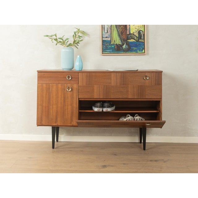 Classic shoe cabinet from the 1960s. Walnut veneer body with two drop-down doors, one drawer, one door, three shelves, and...