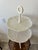 Beautiful white ceramic two tier serving stand featuring embossed leaf-pattern plates and a unique tripod pedestal base....