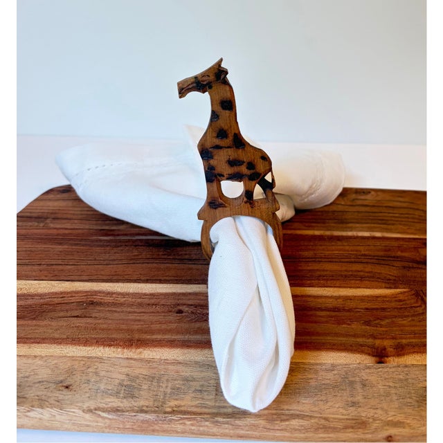 A charming set of six vintage hand-carved wood napkin rings, each featuring an elongated giraffe form with carved and...