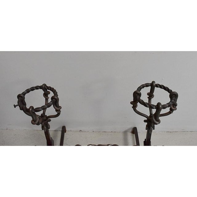 Pair of twisted wrought iron andirons, with snake decorations, Renaissance style. The feet are decorated with scrolls....