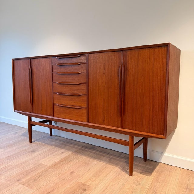 Danish modern teak highboard, circa 1960s, with a beautifully balanced, architectural form. The facade is defined by a...