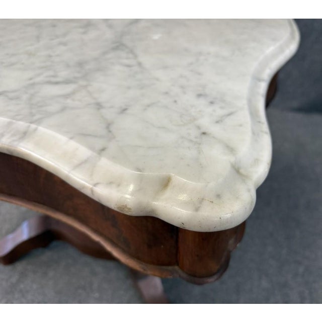 This 19th century flamed mahogany center table is topped with a beautifully contoured white marble slab that highlights...