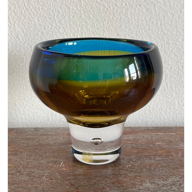 A mid-century modernist studio glass vase from Kosta Sweden. In jewel tones of amber and sapphire, suggesting waves and...