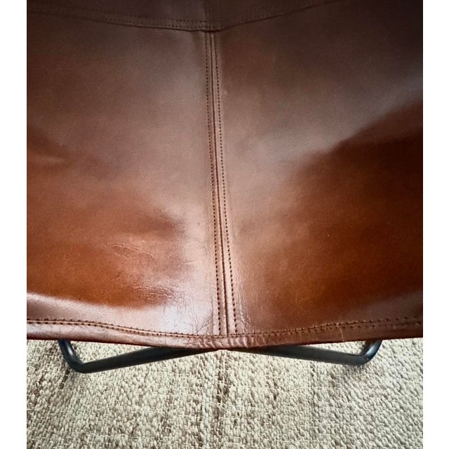Vintage leather butterfly chair with cognac leather sling seat and black metal frame. Natural patina and visible seam...