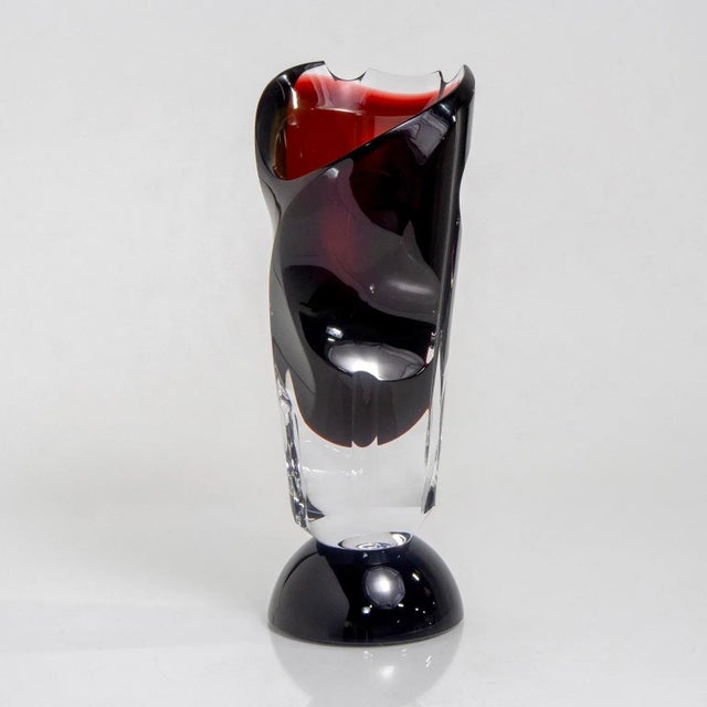 Circa 1930s deep red and clear art glass vase with pedestal base and faceted, asymmetrical body and irregular rim.