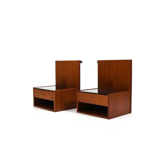 Pair of hanging bedside tables in teak by Hans Wegner for Getama Denmark, 1960s. Each with drawer and black glass. This...