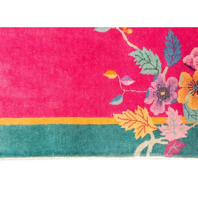 An early 20th century Chinese Art Deco rug with a fuchsia field surrounded by a thin gold and wide turquoise border, and...