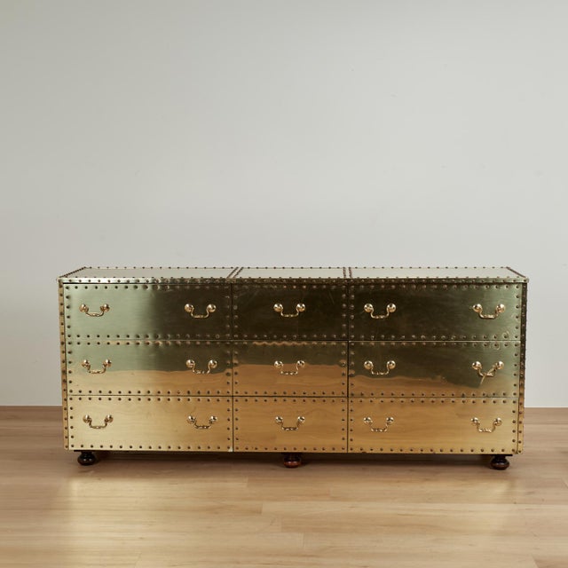 Chic mid century triple dresser crafted in riveted brass panels over a wood frame in sleek modern form with nine drawers...