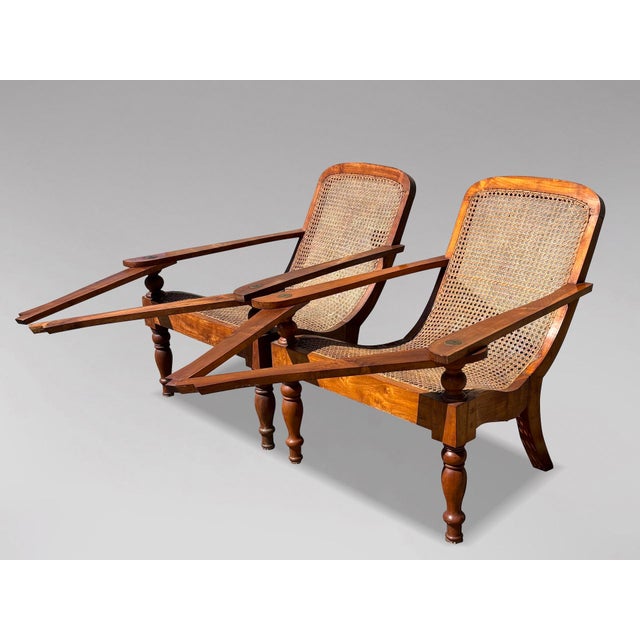 A Handsome Matched Pair of Original Anglo-Indian Teak and Cane Plantation Chairs, circa 1910–1920. Crafted in solid teak...