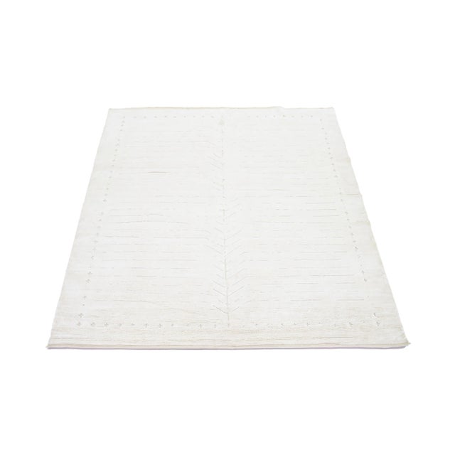 This wool rug, expertly hand-knotted, features a contemporary Moroccan design in subdued beige tones contrasted against a...