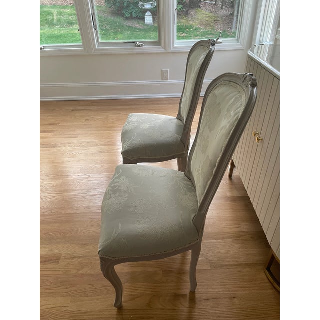 Pair of French Style Provincial side chairs with light gray silk damask newly upholstered with white brocade trim. These...