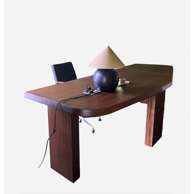 Sculptural desk crafted in mahogany, featuring an elongated top with beveled edges and architectural legs.