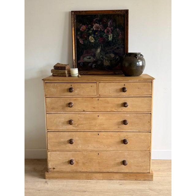 A large antique English pine chest of drawers with a clean, straightforward form and a warm, natural finish. The layout...