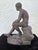 This finely cast sculpture depicts a seated nude youth in a contemplative pose, inspired by Classical Greek and Roman...