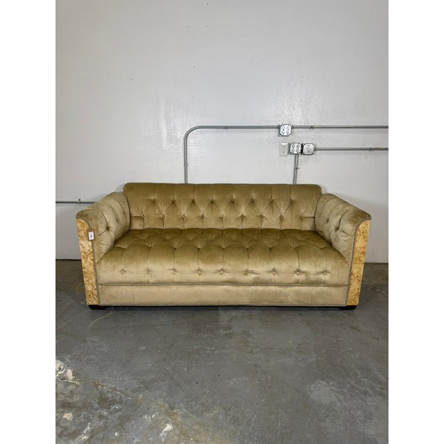 Vintage tufted sofa upholstered in elegant champagne-colored velvet with distinctive burlwood side paneling. Features deep...