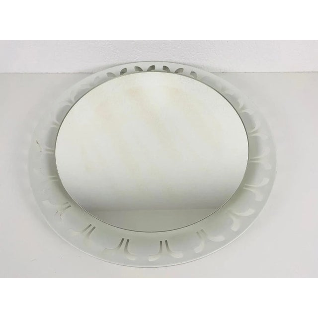 A hillebrand illuminated wall mirror from the 1950s made in germany. The mirror has a round metal design. There are e14...