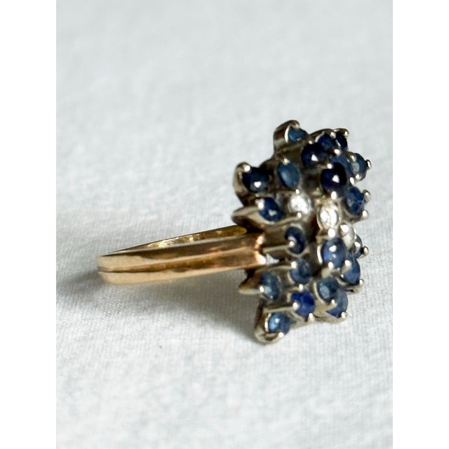 A striking vintage 14K yellow gold cluster ring featuring a dramatic cascade of blue sapphires and diamonds arranged in an...
