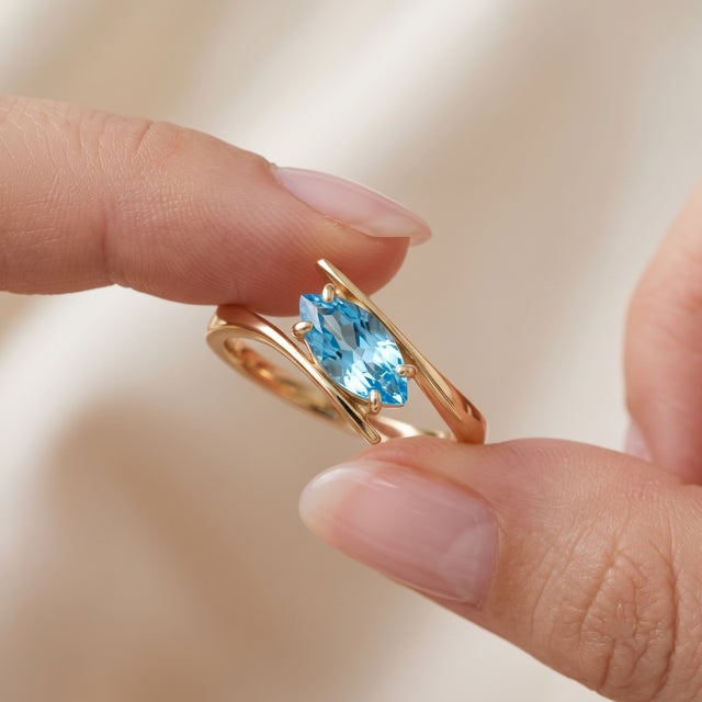 Capture serenity and sophistication with this lovely bypass ring featuring a brilliant marquise-cut Blue Topaz. Designed...