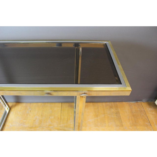 Chrome metal console and golden metal, top of smoked glass, around 1970, set in very good condition This piece is designed...