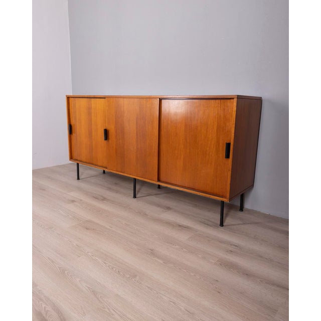 Teak wood sideboard with three sliding doors, with black metal legs and handles, Italian design, 1960s.