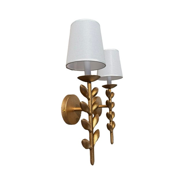 Pair of gold botanical wall lamps. Features an elongated stem with organic textured, symmetrical leaves and fabric...
