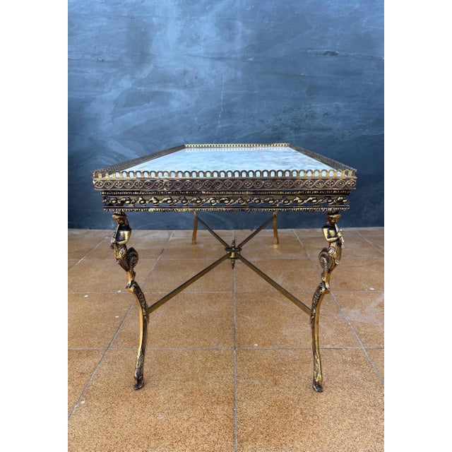 Elegant neoclassical style coffee table featuring a marble top and a finely crafted gilt metal structure. The table stands...