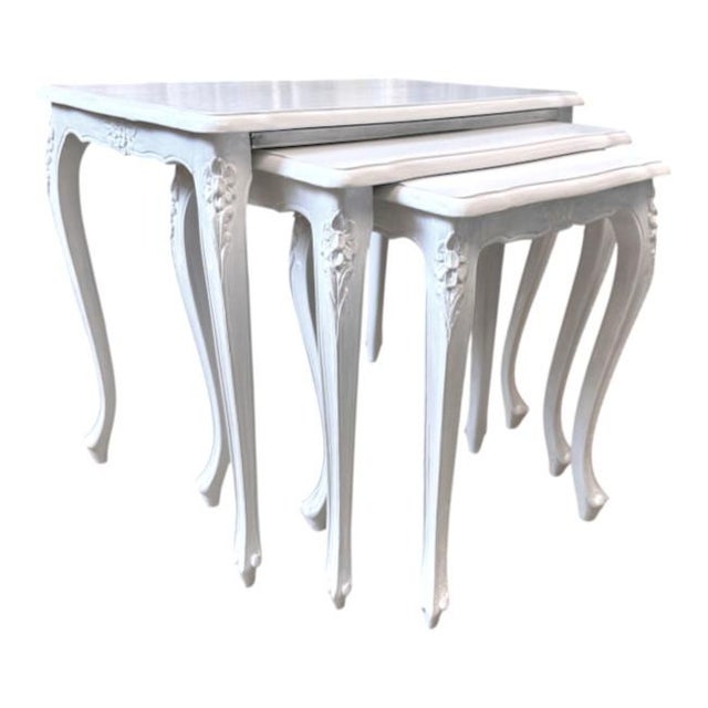 Elegant vintage set of three nesting tables showcasing classic French Provincial / Louis XV-inspired design. Each table...
